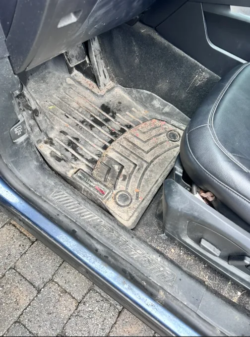 Front floor mat caked in dirt and debris before detailing