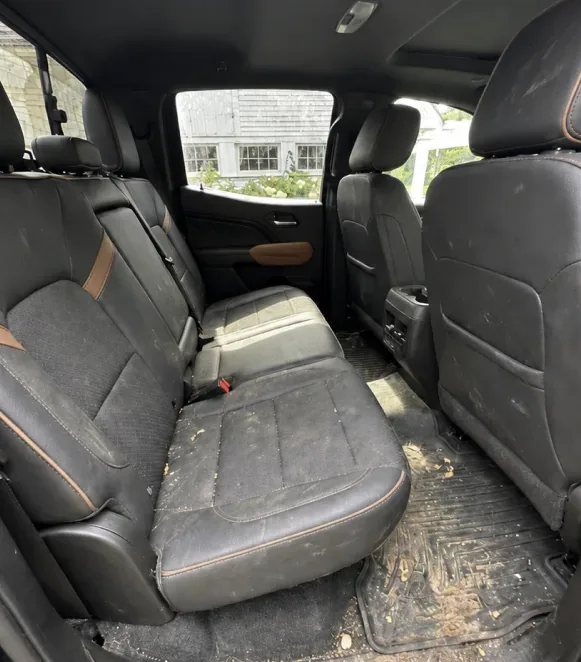 Truck rear bench seat covered in crumbs and mud before detailing